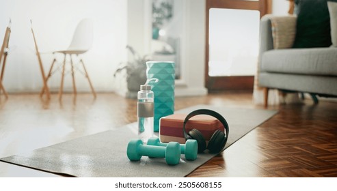 House, floor and mat with gym equipment in room for home cardio workout, health or wellness. Water, headphones and interior with dumbbell on ground for exercise music, streaming or training hydration - Powered by Shutterstock