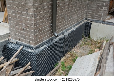 House Foundation Basement Waterproofing, Damp Proofing With Rigid Insulation. Installation Of A Dimpled Waterproofing Membrane On The Exterior Basement Wall And Rain Gutter Downspout Drain Pipe. 