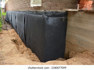 House foundation waterproofing. Installation of a dimpled waterproofing membrane on the exterior brick house basement wall.  - Shutterstock ID 2180077099