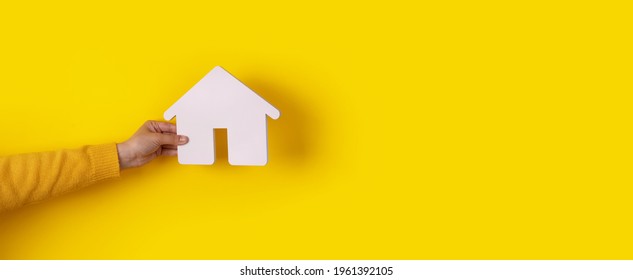 house in hand over yellow background, concept of buying a home on credit, panoramic mock-up - Shutterstock ID 1961392105