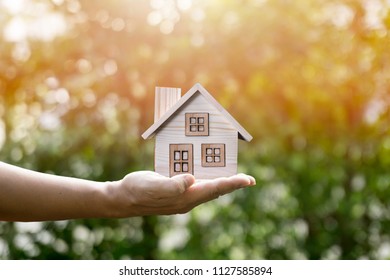 House in hand and sunlight show savings money and savings to buy a home or buy real estate. Or show a home loan or divide the investment for retirement. Or for the future Concept of money. - Shutterstock ID 1127585894