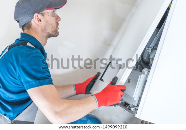 House Heating Unit Repair by\
Professional Technician. Closeup Photo. Home Equipment\
Issues.\
\
\
\

