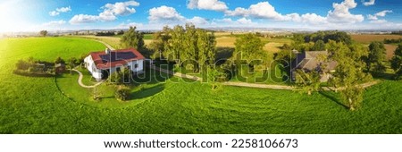 House in idyllic countryside in Austria, Europe, with a solar panel on the roof surrounded with beautiful vast meadow and trees
