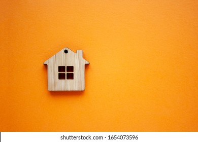 House, Insurance And Mortgage, Buing And Rent Concept. Small Wooden House Toy On Orange Background Top View Copyspace