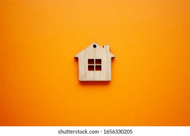 House, Insurance And Mortgage, Buing And Rent Concept. Small Wooden House Toy On Orange Background Top View 