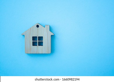 House, Insurance And Mortgage, Buing And Rent Concept. Small Wooden House Toy On Blue Background Top View With Copy Space