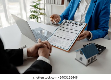 House insurance paperwork, A realtor is explaining home insurance documents to a buyer in his office at the company, Sign home insurance documents, make an agreement together.