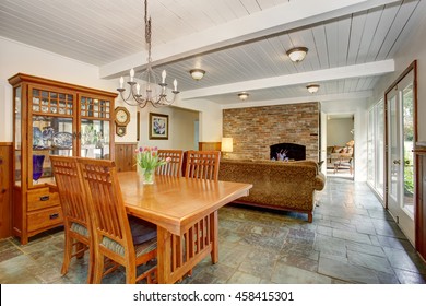 House Interior With Open Floor Plan. Dining Room With Wooden Furniture Set, Living Room With Brick Wall And Fireplace.