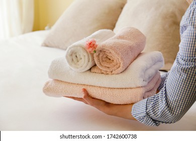 House keeping lady changing the set of folded and stacked towels in hotel room with freshly made bed, perfectly clean and ironed sheets in natural sun light. Close up, copy space for text. - Shutterstock ID 1742600738