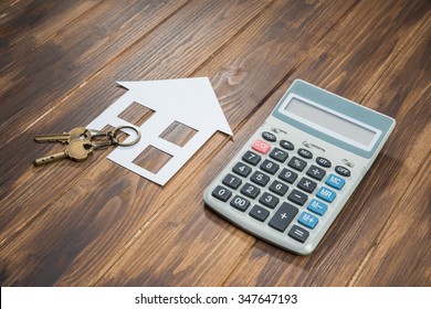 House And Key With Calculator On Wooden Background