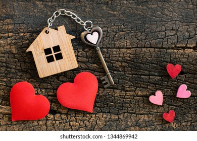 House key in heart shape with home keyring on old wood background decorated with mini heart, home sweet home concept, copy space