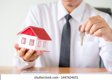 House key in home insurance broker agent's hand protection or in salesman person giving to buyer customer