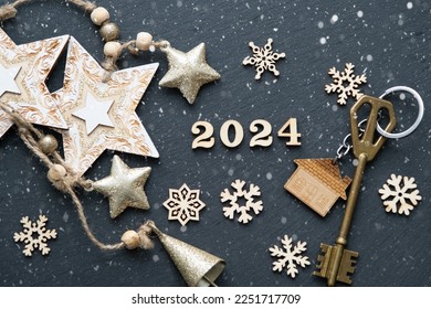 House key with keychain cottage on black background with stars, snowflakes. Happy New Year 2024-wooden letters, greeting card. Purchase, construction, relocation, mortgage - Powered by Shutterstock