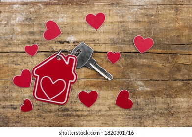House key on a house shaped keychain resting on wooden floorboards concept for real estate, moving home or renting property