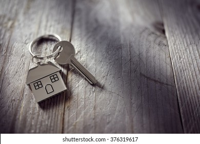House key on a house shaped keychain resting on wooden floorboards concept for real estate, moving home or renting property - Shutterstock ID 376319617