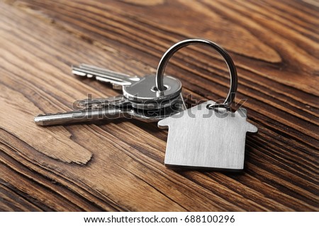 House key on  house shaped keychain  on wooden floorboards