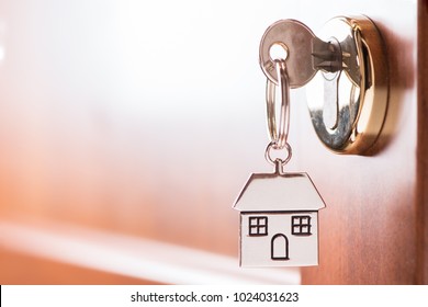 House Key On A House Shaped Silver Keyring In The Lock Of A Entrance  Brown Door