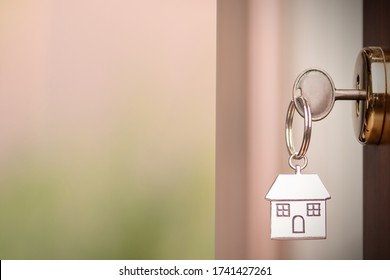 House key on a house shaped silver keyring in the lock of a entrance brown door with copy space