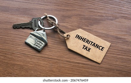 A house key with a tag written with Inheritance Tax on wooden background. - Shutterstock ID 2067476459