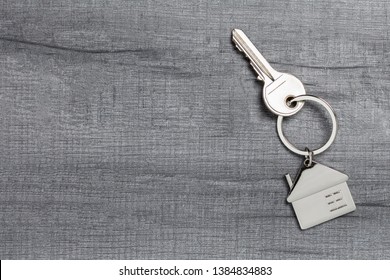 House keychain and key on wooden table with copy space