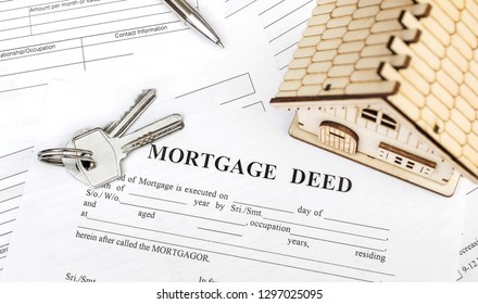 House Keys With Pen And Model Of House On Mortgage Deed Form. Close Up. Top View.