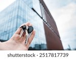 House keys in real estate agent against new skyscraper glass office. Concept of moving home or renting property