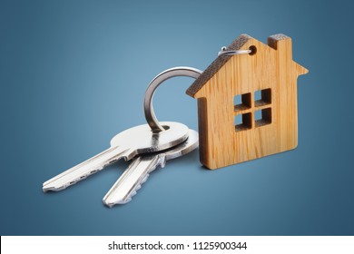 House keys with house shaped keychain on blue background