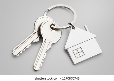 House keys with house shaped keychain on gray background