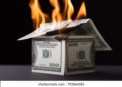 House Made Up Of Banknote Burning In Fire Against Black Background