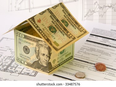 A house made by US Dollar banknotes on several charts and a credit application form,  accompanied by some coins