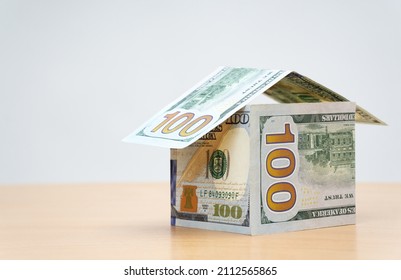 House made from folded one hundred dollar bills on a wooden table. Saving money for a mortgage deposit. - Powered by Shutterstock