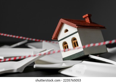 House model and broken dishes on black table depicting destruction after earthquake. Space for text - Shutterstock ID 2235765053