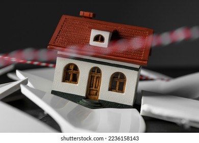 House model and broken dishes on black table depicting destruction after earthquake, closeup - Shutterstock ID 2236158143