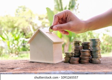 House Model And Coins Stacks On Wooden Table. Save And Investment Money For Prepare In The Future - Saving Money Concept.