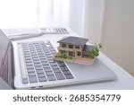 A house model and a computer. The image of a real estate agent