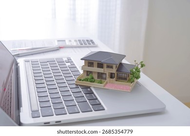 A house model and a computer. The image of a real estate agent