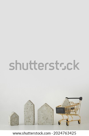 House model in mini shopping cart on the white background. Buy a house. Concept for property ladder, mortgage and real estate investment. Free space for text, copy space, modern layout.