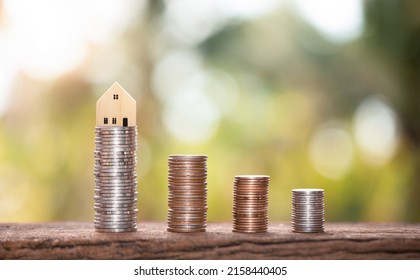 House Model On A Pile Of Coins On A Wooden Table With A Nature Blur Background, Savings Concept For Home Purchases, Home Installments, Home Mortgages, Collateral, Banking, Business, And Finance.	