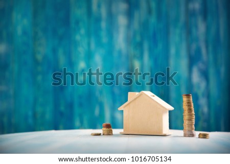house model on wooden background with coins. Property price concept