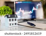 House model, pen and notepad on table with stock market chart, real estate market ,investment trading