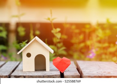 A house model and red heart with family love concept, on the wooden floor in public park.