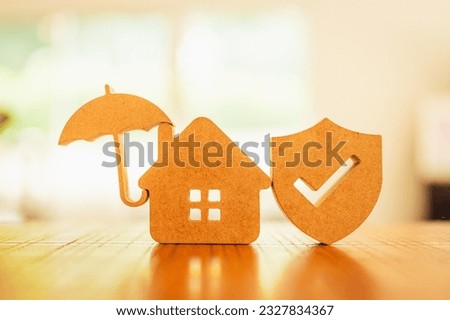 House model with umbrella and shield protect icon on wood table, concepts of contract to buy, get insurance or loan real estate or property background.	