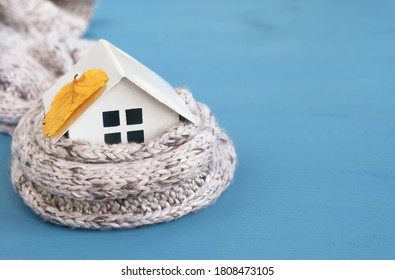 House model wearing knitted scarf and autumn leaf on wooden blue table. Heating system, cold season concept. Copy space, close up - Powered by Shutterstock