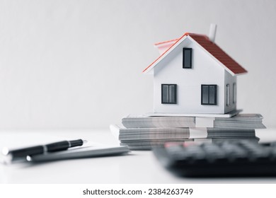 House with money. Concept of finance or refinance real estate. Symbol of house stands against background of us dollars. Property investment. Home mortgage loan rate. Saving money for retirement.