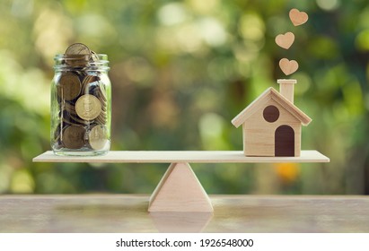 House mortgage and family financial management concept: Wooden home and heart, Family member and US dollar hessian bags on balance scale. Prepare expenses for the purchase of a residence. - Shutterstock ID 1926548000