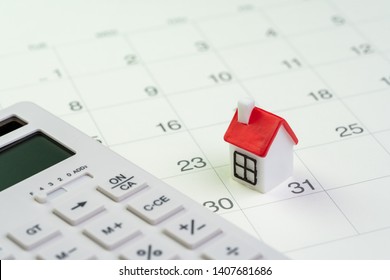 House Mortgage Payment And Installment Schedule Concept, Small Miniature House On End Of Month Calendar With Calculator.