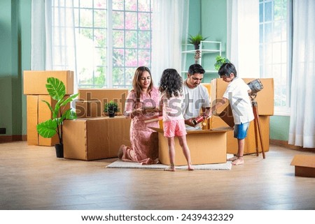House move concept. Happy Indian young family sitting on the floor in new home