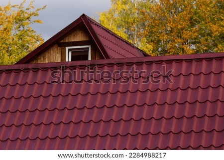 House with new brown metal tile roof and rain gutter. Metallic Guttering System, Guttering and Drainage Pipe Exterior.