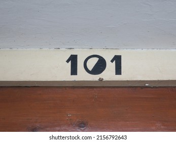 house number 101 painted  in black on a wooden frontdoor