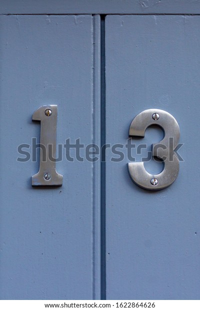 House number 13 as\
bold steel digits on a light blue wooden front door with a vertical\
line separating them
